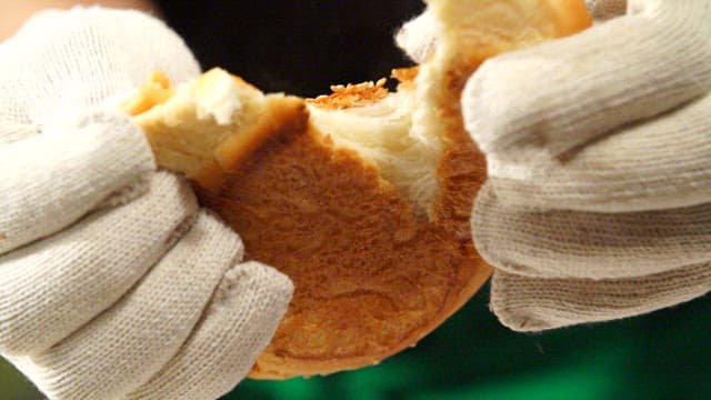 Hands tearing a freshly baked burger bun