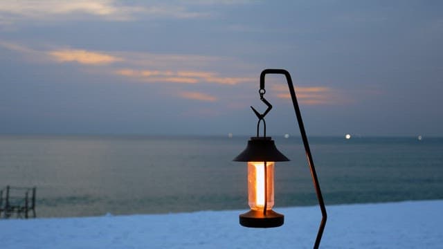 Glowing lantern hanging by the beach at sunset