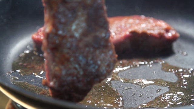 Beef steak being cooked in a frying pan
