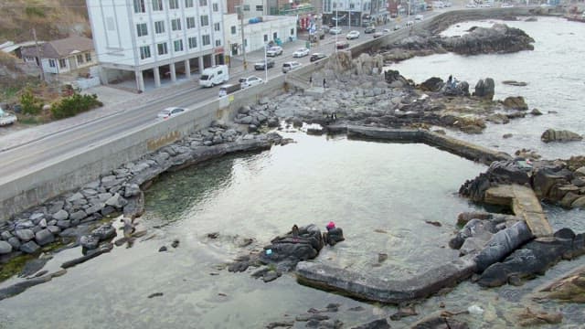 Coastal road with rocky shore and people