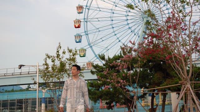 Man standing near a ferris wheel in a park
