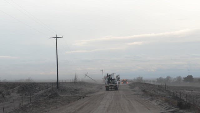 Utility trucks loaded with industrial equipment runs on a dirt road