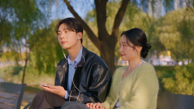 Couple sharing earphones on a park bench