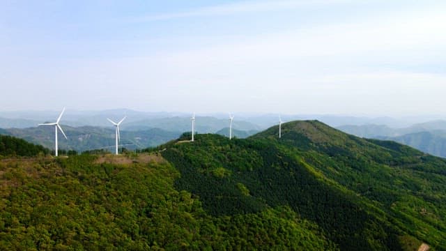 Wind turbines on a lush mountain ridge during daytime