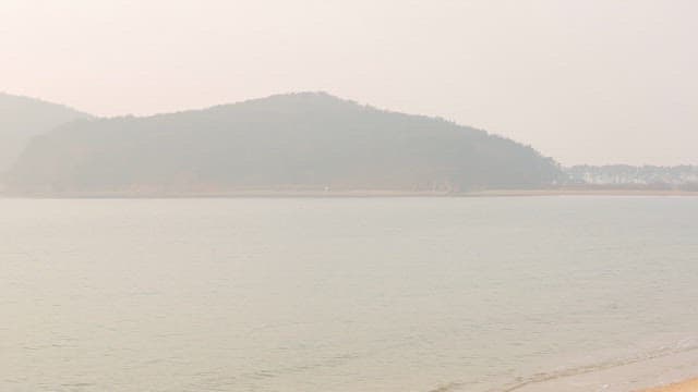 Hazy Coastal Landscape with a Serene Beach