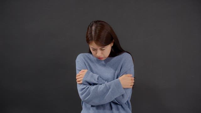 Woman shivering with anxiety and cold, stroking her arm