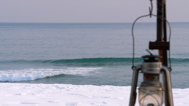 Snowy beach with a camping lantern during a calm morning