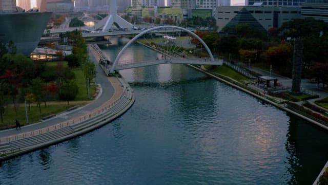 Serene Sunset Over a Modern City Park with Arch Bridge