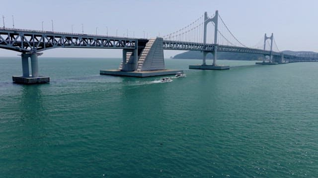 Yachts passing under the Gwangan Bridge on a clear day with lots of cars