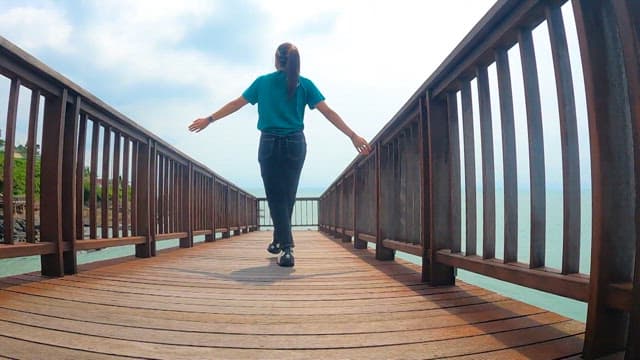 Woman walking on peaceful coastal wooden deck