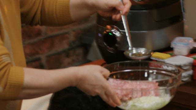 Adding pepper on minced meat and chopped onions in a bowl