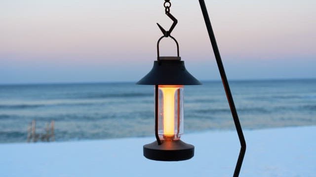 Glowing lantern hanging by the beach at sunset