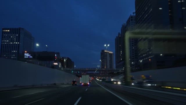 Car Crossing the Road Between Buildings at Night