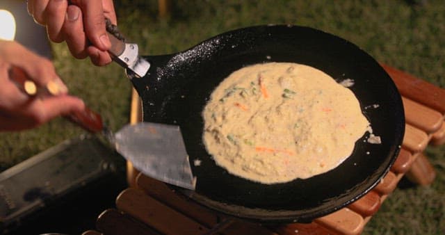 Preparing Vegetable Pancakes Outdoors at Night during Camping