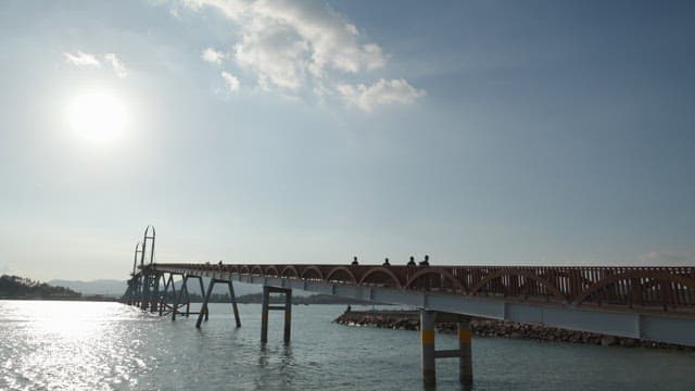 People walking across a scenic sunny bridge
