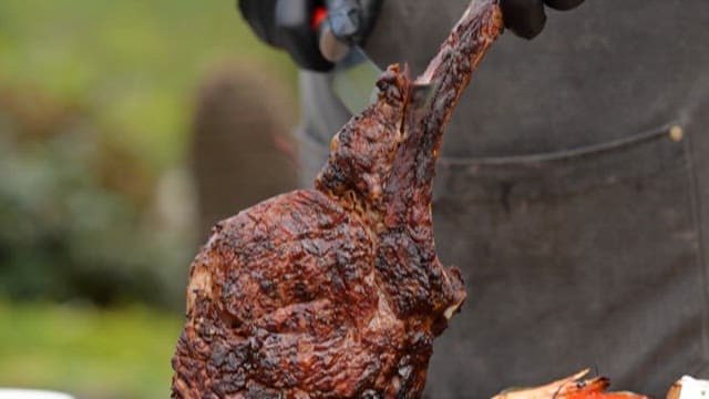 Person holding and cutting a grilled steak