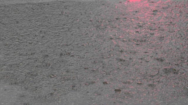 Raindrops creating ripples on a pavement