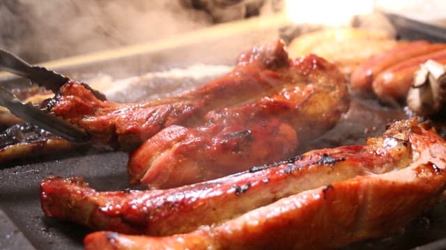 Pork being grilled on a hot barbecue grill
