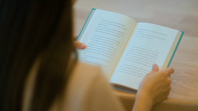 Focused person reading a book indoors