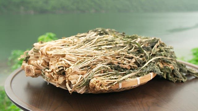 Dried radish greens in a wooden basket with a green natural background