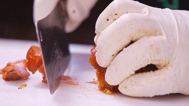 Slicing cooked pig trotters with a cleaver