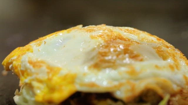 Spreading tomato sauce on toast with fried egg