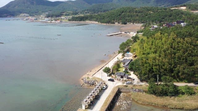 Peaceful coastal landscape with a view of green, lush forests and Hanok houses