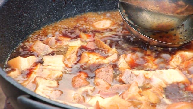 Braised pork shank simmering in a pan