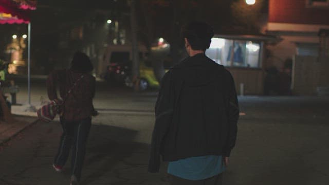 Man and a woman running on a dark street at night
