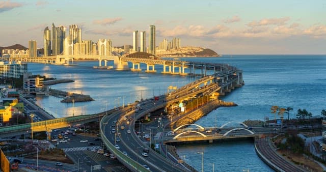 From day to night view of a bustling port city Busan with tall skyscrapers and Gwangan Bridge