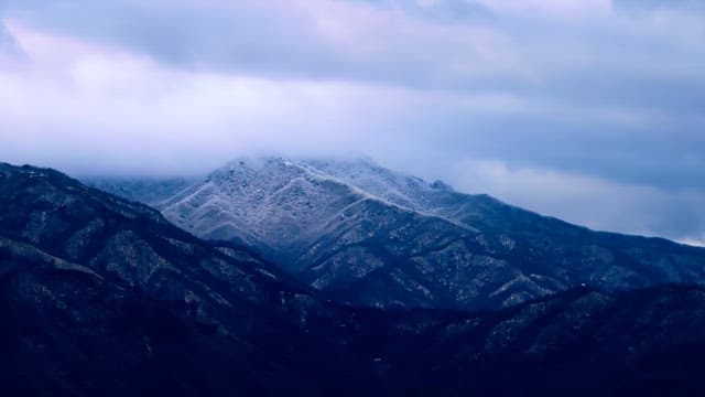 Snow-covered mountains under cloudy skies