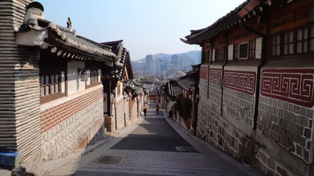 Alley of traditional Korean village in the afternoon with a modern city skyline
