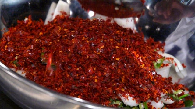 Mixing red pepper flakes with vegetables