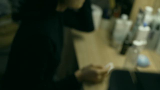 Woman Looking in the Mirror at a Dressing Table with Some Cosmetics