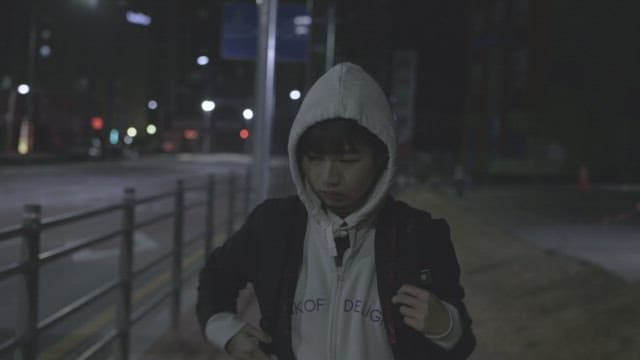 Girl walking alone on a dimly lit street at night with a pensive expression