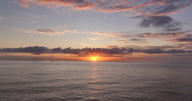Sunset over the calm ocean with clouds