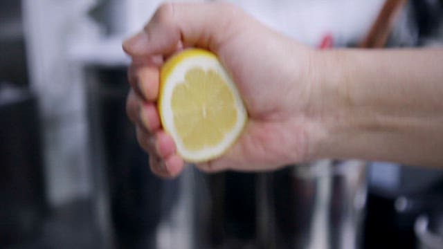 Lemon juice being squeezed into a pan with boiling cream sauce