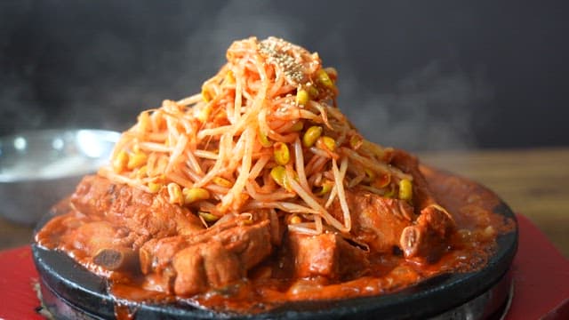 Steaming plate of spicy braised pork libs with bean sprouts