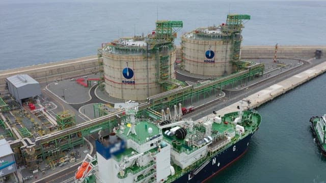 Two large storage tanks and an LNG ship docked at a port