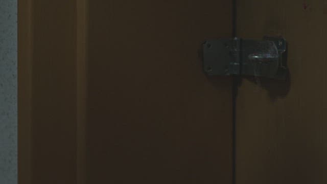 Person putting a lock with combination lock on a wooden door