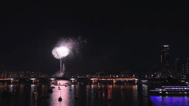 Fireworks over a city river at night