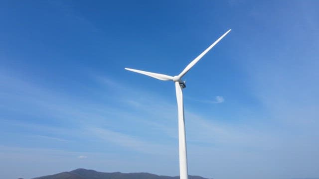 White wind turbines spinning against a clear blue sky