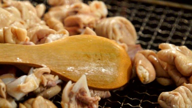 Grilling pork intestines on a grill