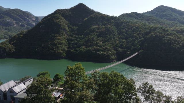 View of a Suspension Bridge with Scenic Lake and Mountain