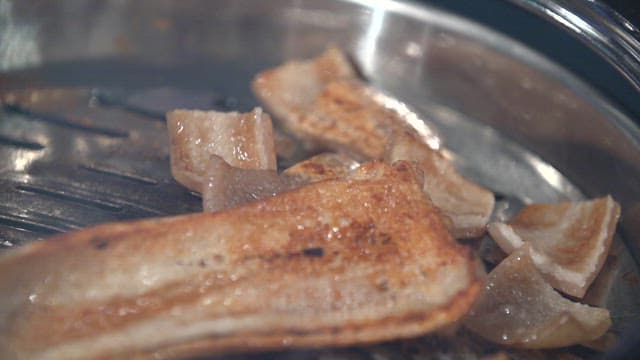 Cooked pork rinds cutting with scissors