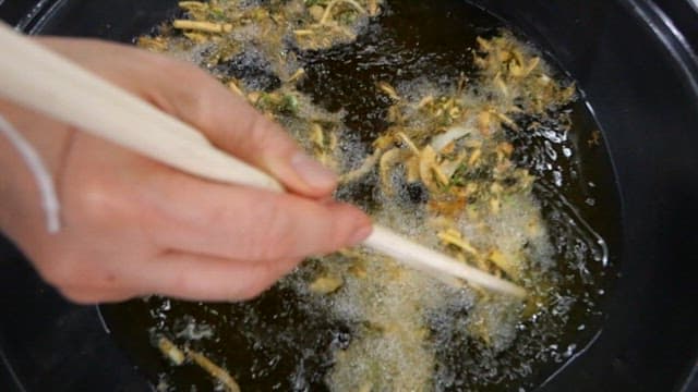 Frying sweet potato in hot oil with chopsticks