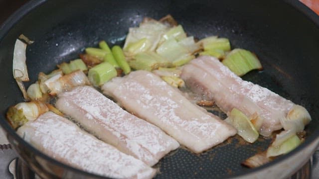 Frying green onions and hairtail in oil in a frying pan