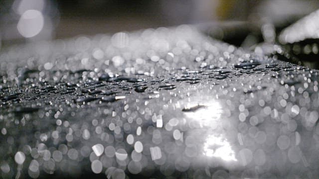 Raindrops glistening on a smooth surface at night