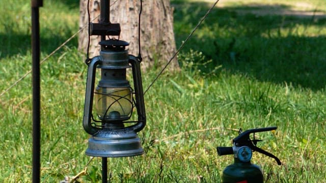 Camping lantern and propane torch in a grassy outdoor setting