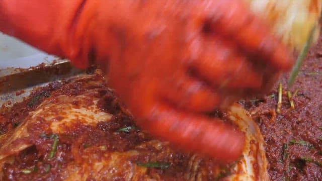 Making kimchi by adding chili pepper seasoning to cabbage